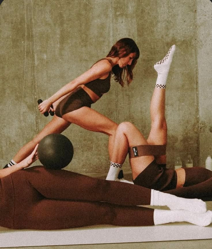 Two people practicing mat Pilates with resistance equipment